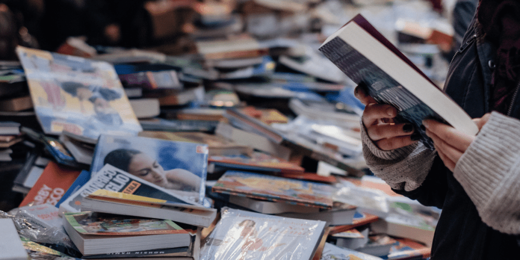 a person holding a book in front of a pile of books