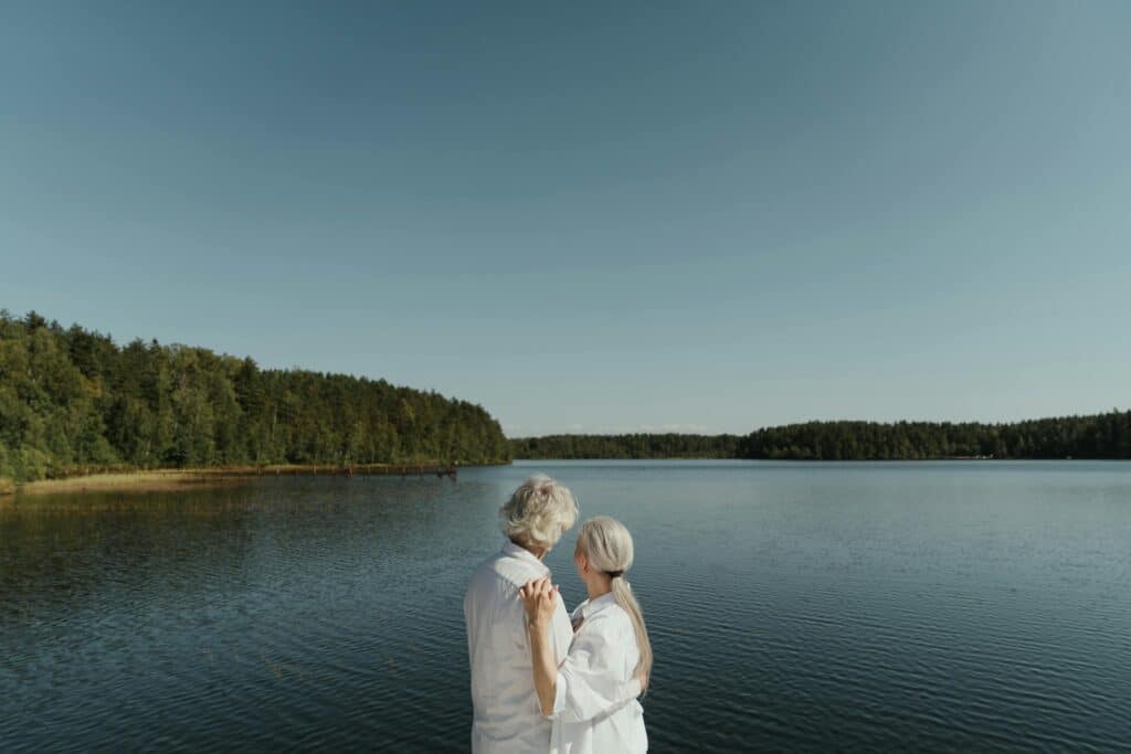 A senior couple embraces by a serene lakeside, showcasing love and connection.