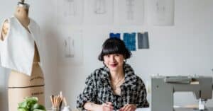 Creative fashion designer smiling at work in her studio, engaging in her craft.