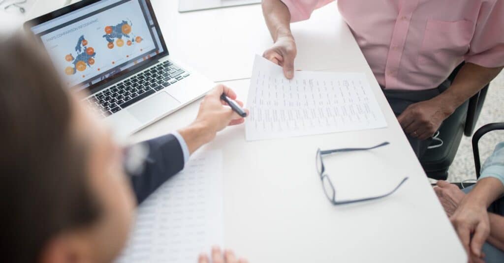 Senior couple reviewing documents with consultant at office desk with laptop.