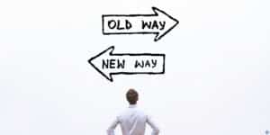 a person standing in front of an old way sign and a new way sign