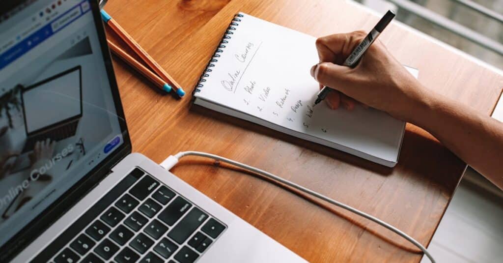 Online Courses for Adults in 2025: Compare Top Providers 10 A person writing notes while researching online courses on a laptop in a home setting.