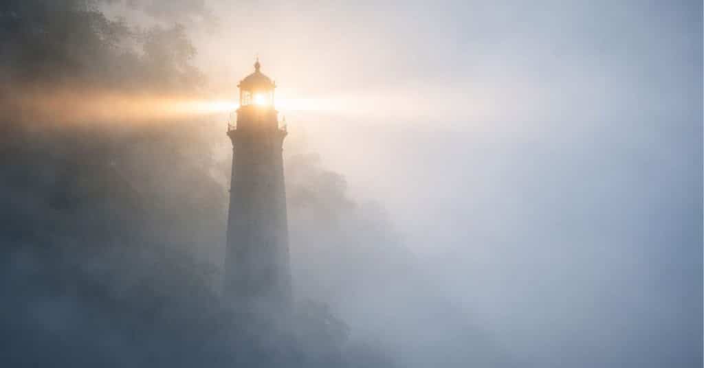 A lighthouse shining through fog, symbolizing clarity and focus under pressure.