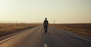 Person walking alone on a quiet road in soft light