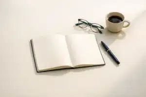 Open notebook, navy pen, glasses and coffee on an ivory desk — pausing to reconsider a career change at 40