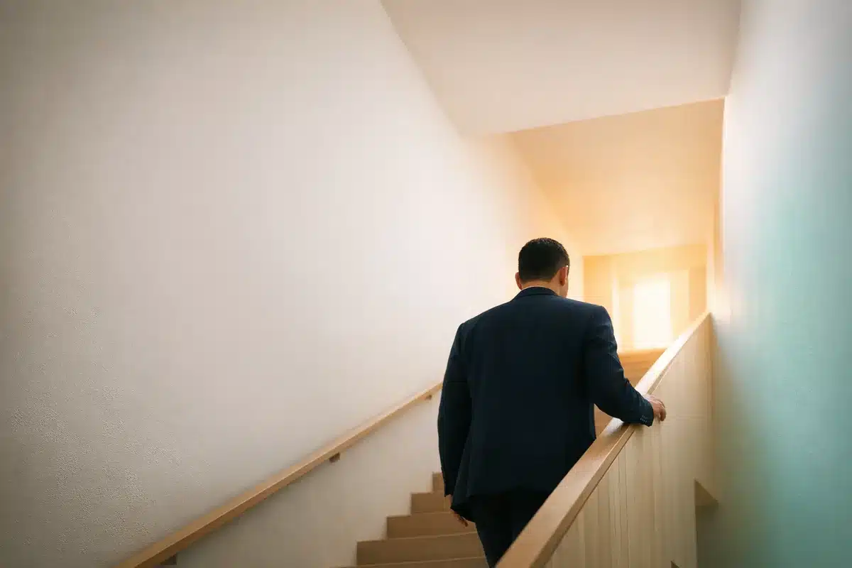 Professional walking up a bright staircase, representing career progression through a focused course and real-world practice